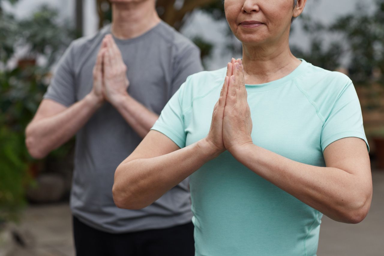 team-04 Senior couple in a meditative yoga pose outdoors, promoting wellness and a healthy lifestyle.